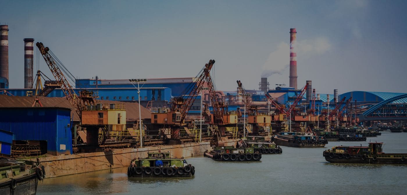 Cranes and barges working an industrial port.
