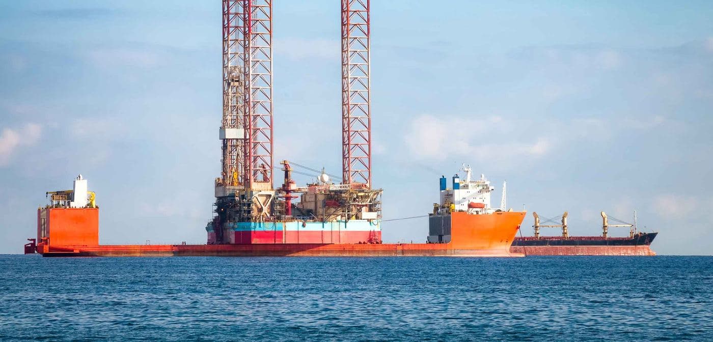 An offshore jack-up rig beside a tanker at sea.